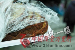 ■解開(kāi)保鮮膜,蛋糕一角有顆耗子屎(紅圈處)。重慶晚報(bào)記者 陸綱 攝